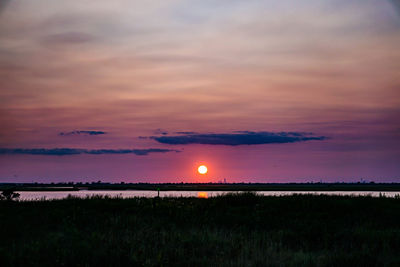 Scenic view of dramatic sky over field during sunset