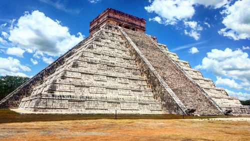 Low angle view of pyramid against cloudy sky