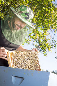 Man holding honeycombs against trees
