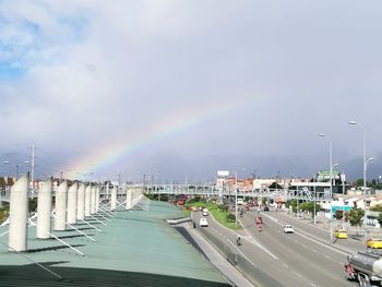 Rainbow over road in city against sky