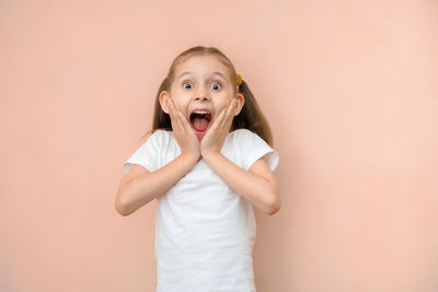 Portrait of cute girl standing against pink background