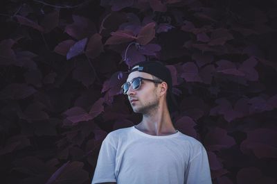 Low angle view of man wearing sunglasses standing against plants