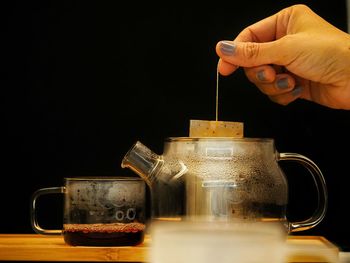 Cropped image of hand holding coffee cup against black background