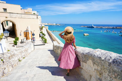 Rear view of woman standing by sea against sky