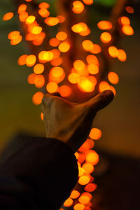 Optical illusion of man holding illuminated tree