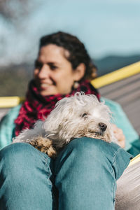 Woman sitting with dog on hammock outdoors