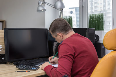 Side view of man writing at office