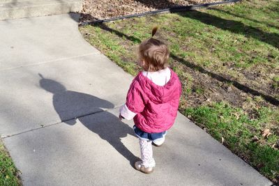 High angle view of baby girl in warm clothing walking on footpath