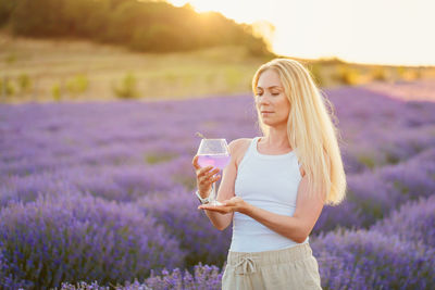 Young woman drinking water while standing at beach