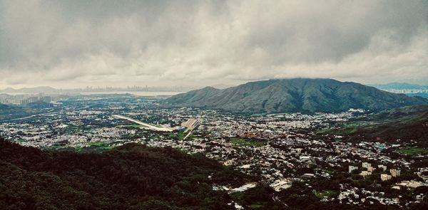 Aerial view of townscape and mountains against sky