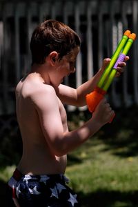 Side view of shirtless boy holding ice cream