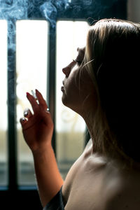 A girl smokes cigarette on black background