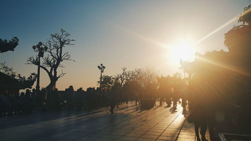 People in city against sky during sunset