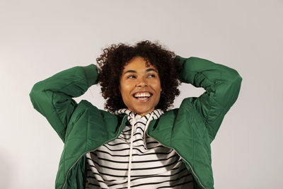 Cheerful young woman with hands behind head against white background