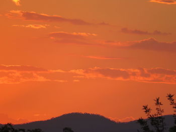 Low angle view of silhouette mountain against orange sky
