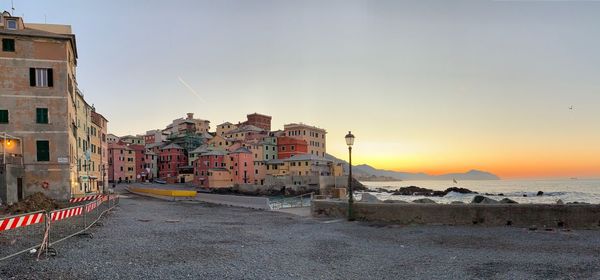 Town by sea against sky during sunset in city