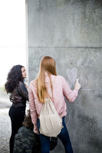 Friends drawing on gray wall in city