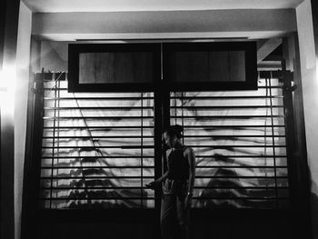 Woman standing by window at home