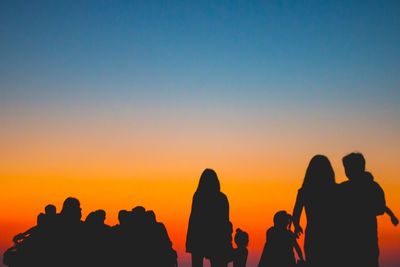 Silhouette people against sea during sunset