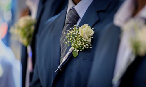 Midsection of groom with bouquet on suit pocket