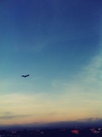 Airplane flying in sky at sunset