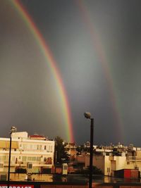 Low angle view of rainbow over buildings in city against sky