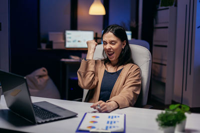 Young woman using mobile phone while sitting on table