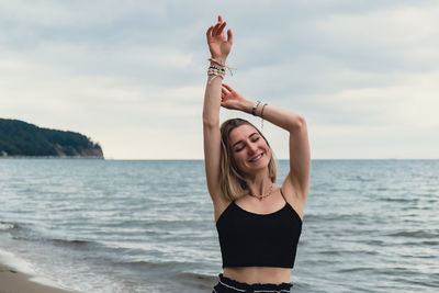 Young woman with arms raised standing at beach
