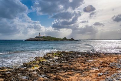 Lighthouse by sea against sky