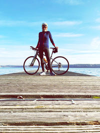 Man riding bicycle by sea against sky