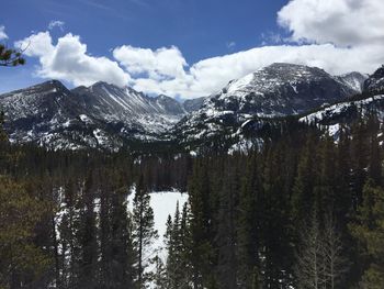 Trees with mountain range against clouds