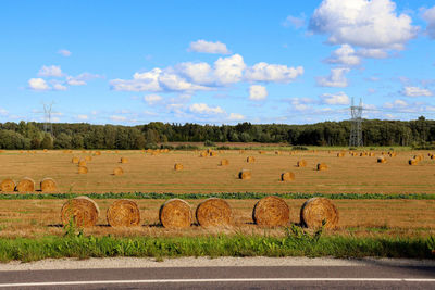 Hay bales on field against sky