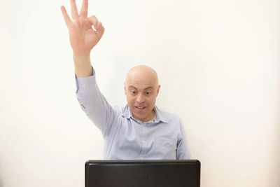 Businessman gesturing ok sign while using laptop in office