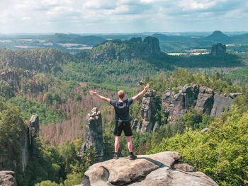 Man shouts greetings to valley bellow carolafelsen rock, grossen dom and jagged schrammsteine rocks