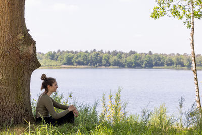 Woman sitting by lake