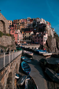 Boats moored at harbor by buildings in city against sky