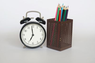 Close-up of clock on table against white background