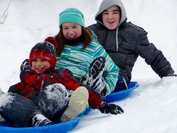 Cheerful siblings tobogganing on ski slope