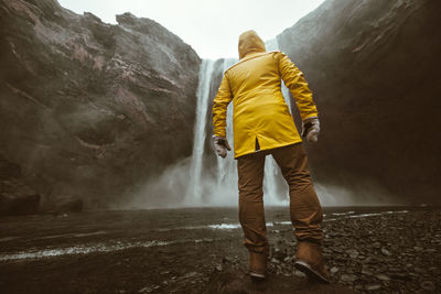 Rear view of man standing at waterfall