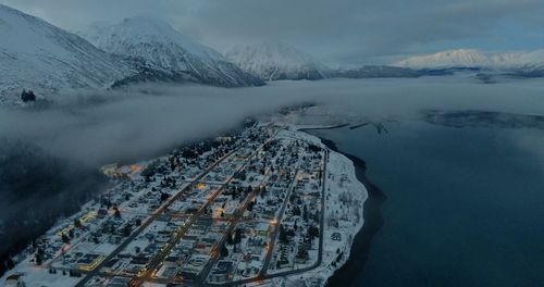 High angle view of buildings by snowcapped mountain against sky