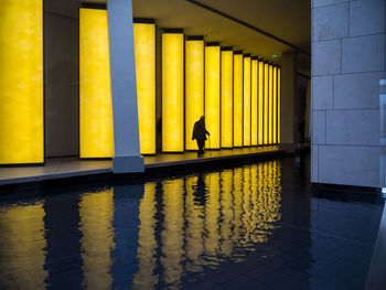 Reflection of man and woman walking on yellow mirror