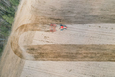 Spring plowing field red tractor aerial photography with drone