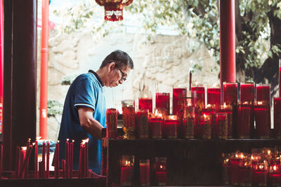 Man standing by lit candles in temple