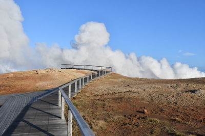 Metallic structure on landscape against blue sky