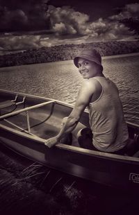 Man sitting on boat in sea against sky