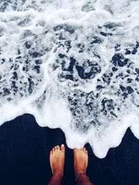 Low section of man standing on shore at beach