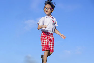 School boy standing against blue sky