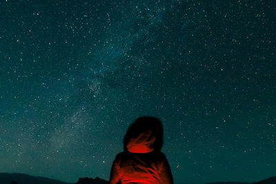 Rear view of woman standing against star field at night