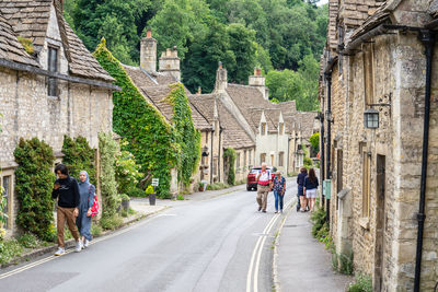 Rear view of people walking on street amidst buildings