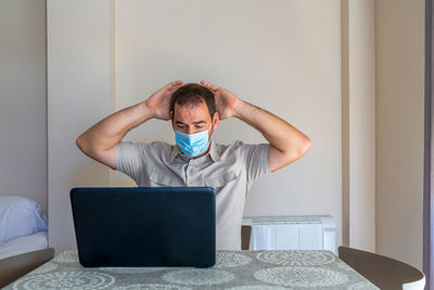 Frustrated man using laptop sitting at home